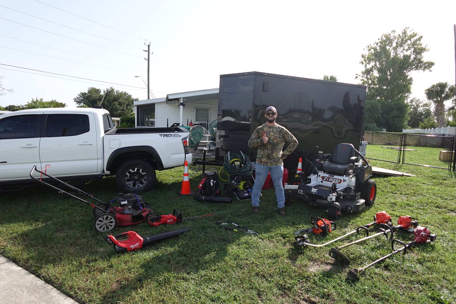 Shipshape owner standing with his truck, trailer, mower, and lawn care equipment